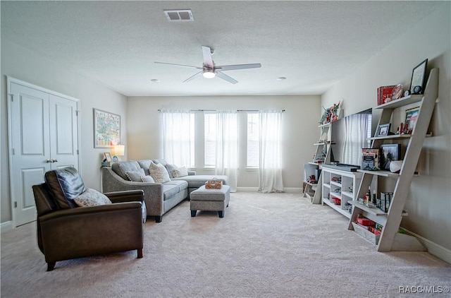 living area with ceiling fan, baseboards, carpet floors, and a textured ceiling