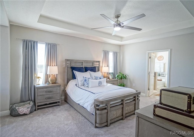 bedroom with baseboards, a raised ceiling, a textured ceiling, and light carpet