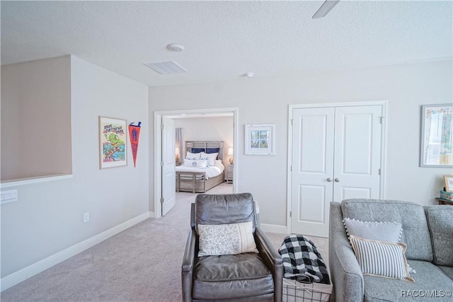 sitting room featuring baseboards, visible vents, carpet floors, and a textured ceiling