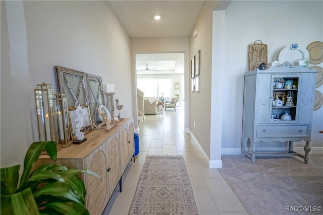 hallway with light tile patterned floors, light colored carpet, and baseboards