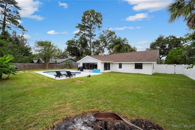 rear view of house featuring a lawn, a fenced in pool, and a patio