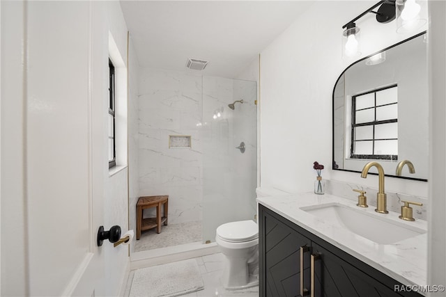 bathroom with tiled shower, vanity, and toilet