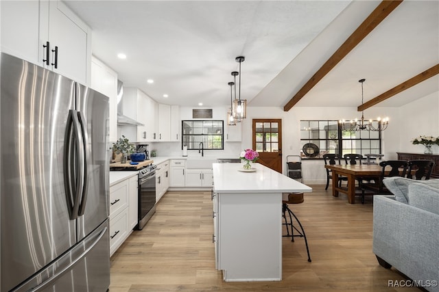 kitchen with a kitchen bar, stainless steel appliances, white cabinetry, light hardwood / wood-style flooring, and a kitchen island