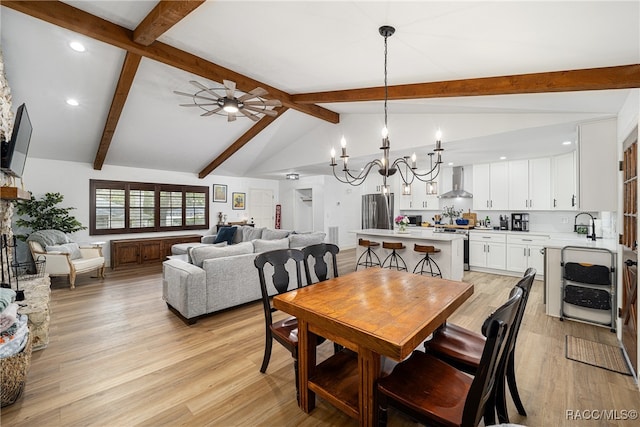 dining area with ceiling fan with notable chandelier, vaulted ceiling with beams, and light hardwood / wood-style floors