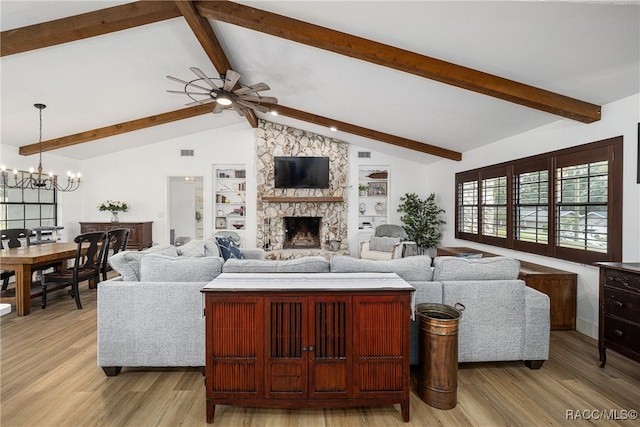 living room featuring vaulted ceiling with beams, a stone fireplace, light wood-type flooring, and ceiling fan with notable chandelier