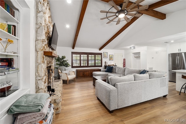 living room with vaulted ceiling with beams, ceiling fan, light hardwood / wood-style flooring, and a stone fireplace