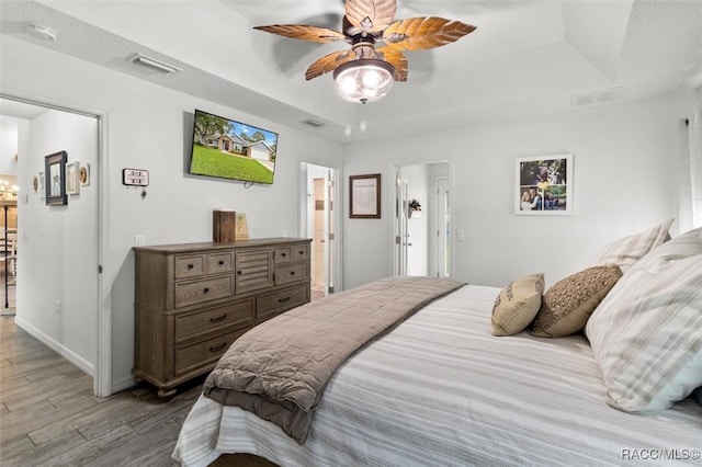 5317 W Tortuga Loop, Lecanto, FL 34461 - bedroom with a raised ceiling, wood finished floors, a ceiling fan, and connected bathroom
