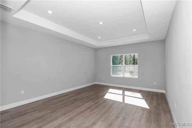 unfurnished room featuring hardwood / wood-style floors and a tray ceiling