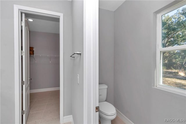 bathroom with tile patterned flooring, toilet, and a healthy amount of sunlight