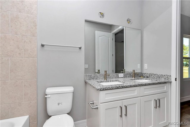 bathroom featuring toilet, vanity, and a bath