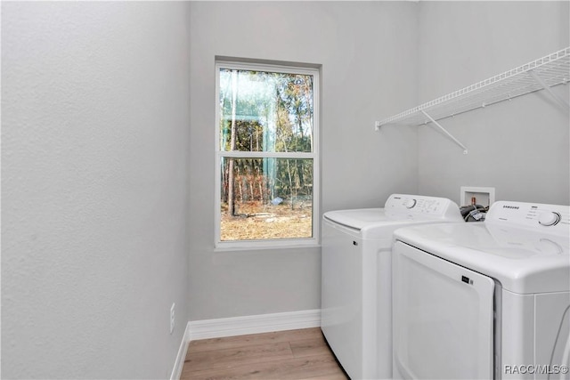 clothes washing area featuring washing machine and dryer and light hardwood / wood-style flooring