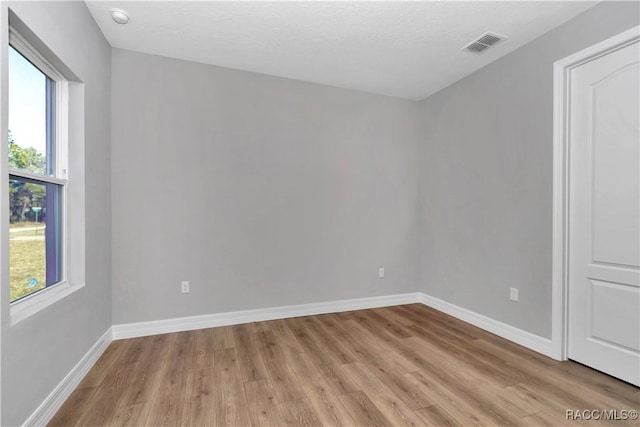 empty room featuring a healthy amount of sunlight and light hardwood / wood-style floors