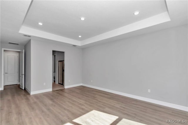 unfurnished room featuring light wood-type flooring and a raised ceiling