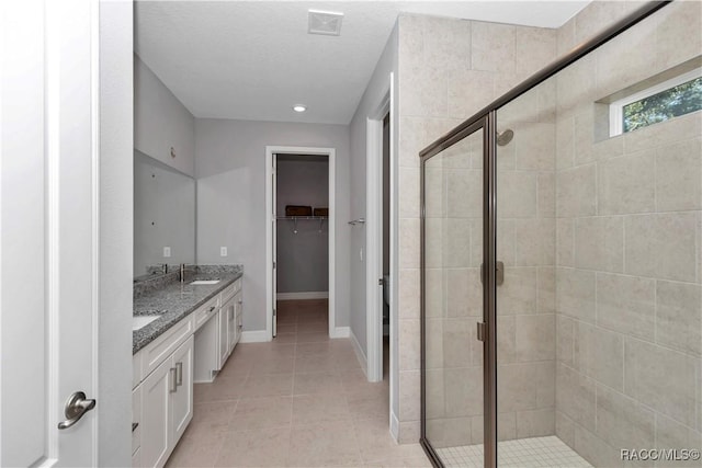 bathroom with tile patterned floors, walk in shower, and vanity