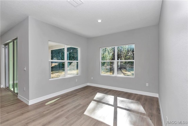 spare room with light hardwood / wood-style floors and a textured ceiling