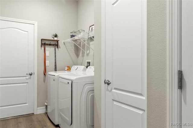 washroom with washing machine and clothes dryer and light hardwood / wood-style floors