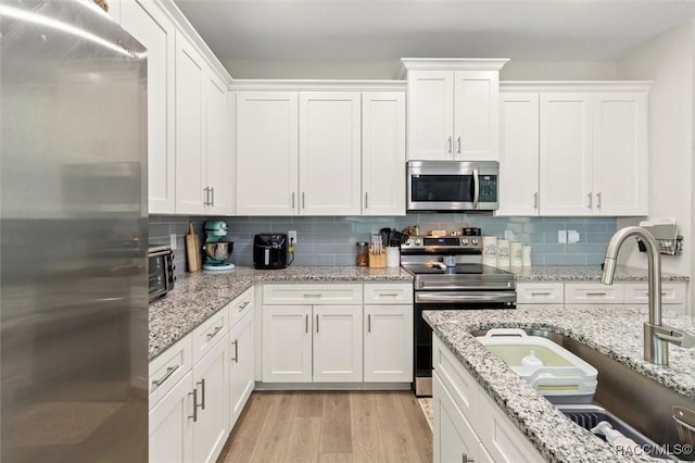 kitchen with white cabinetry, sink, light wood-type flooring, and appliances with stainless steel finishes