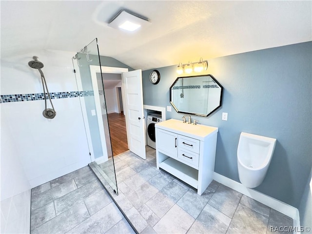 bathroom with vanity, vaulted ceiling, tiled shower, washer / clothes dryer, and toilet