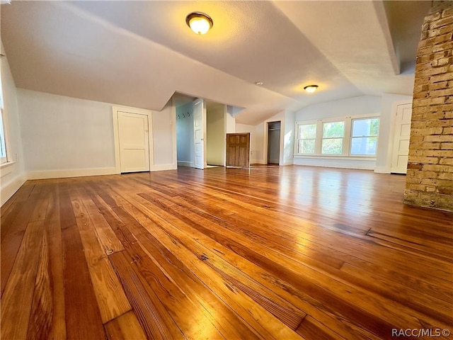 bonus room with hardwood / wood-style flooring and vaulted ceiling