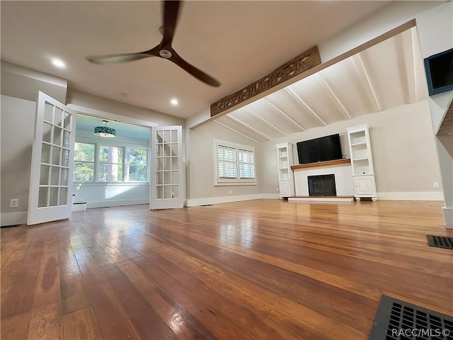 unfurnished living room featuring ceiling fan, french doors, lofted ceiling with beams, and hardwood / wood-style flooring