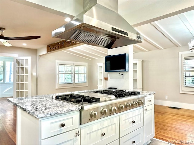 kitchen with white cabinetry, stainless steel gas cooktop, island exhaust hood, plenty of natural light, and lofted ceiling