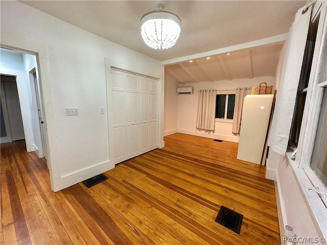 unfurnished bedroom featuring a chandelier, a closet, lofted ceiling with beams, and hardwood / wood-style flooring