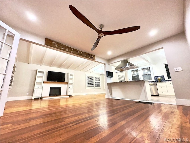 unfurnished living room with vaulted ceiling with beams, ceiling fan, and hardwood / wood-style flooring