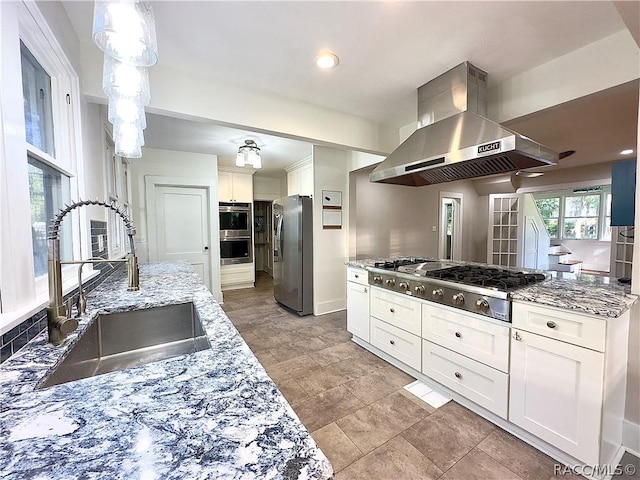 kitchen with appliances with stainless steel finishes, white cabinetry, wall chimney exhaust hood, and sink