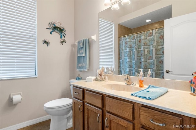 bathroom featuring toilet, vanity, walk in shower, tile patterned floors, and a wealth of natural light