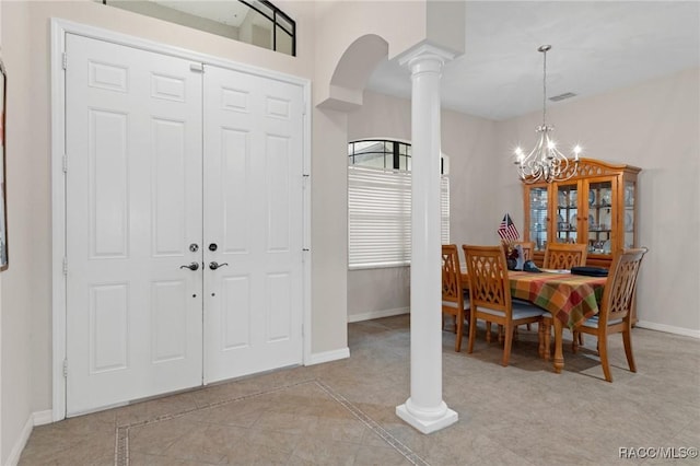 tiled foyer with a chandelier and decorative columns