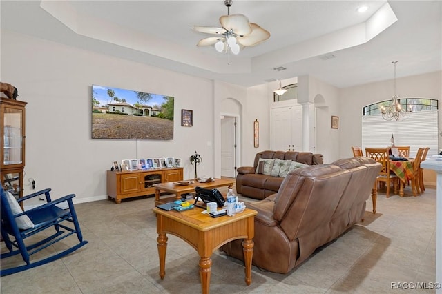 living room with ceiling fan with notable chandelier and a tray ceiling