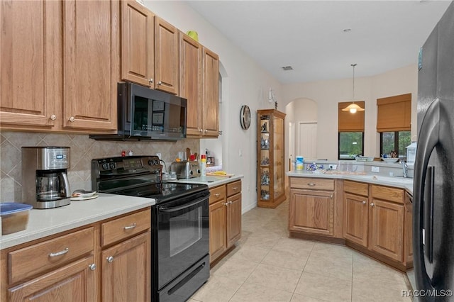 kitchen featuring light tile patterned floors, pendant lighting, backsplash, and black appliances