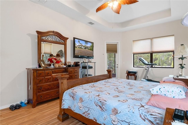 bedroom featuring a raised ceiling, ceiling fan, and light hardwood / wood-style floors