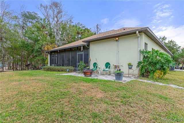 back of house with a sunroom, a fire pit, a lawn, and a patio