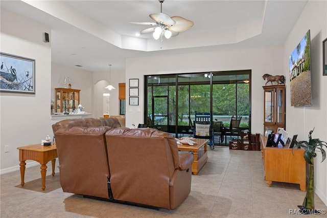 living room with ceiling fan, light tile patterned floors, and a raised ceiling