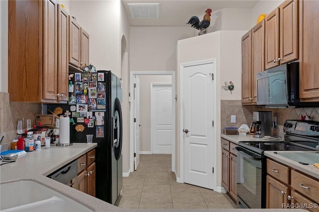 kitchen featuring decorative backsplash, sink, light tile patterned floors, and black appliances