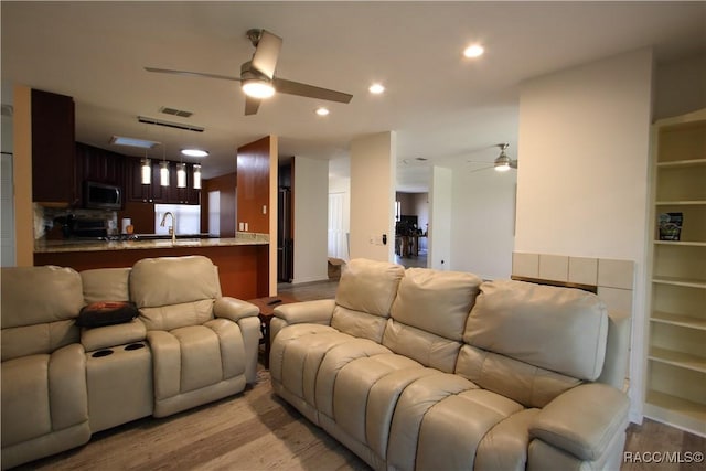 living room featuring light wood-style flooring, a ceiling fan, and recessed lighting