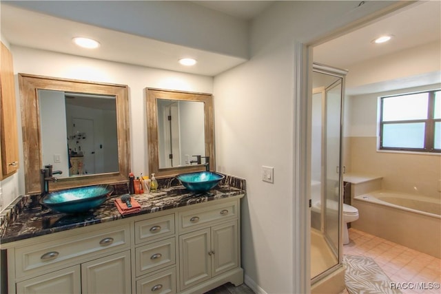 bathroom with double vanity, a stall shower, a sink, and toilet