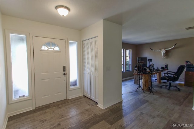 foyer entrance featuring visible vents, baseboards, and wood finished floors