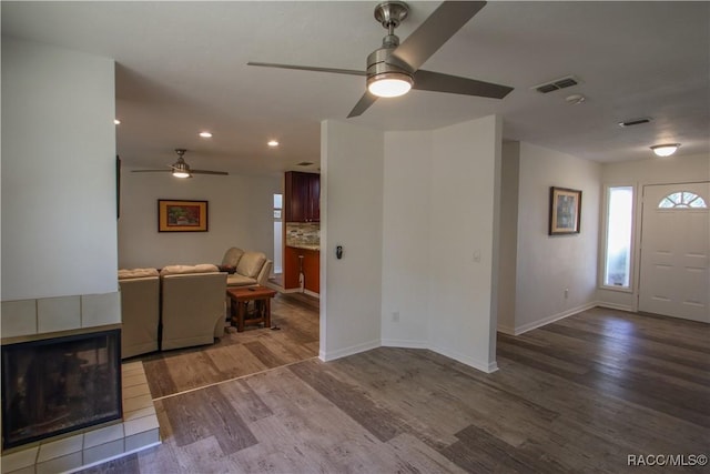 unfurnished living room with baseboards, visible vents, wood finished floors, a fireplace, and recessed lighting