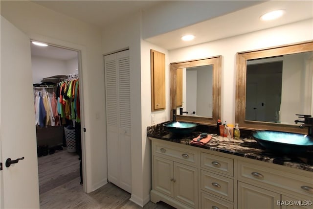 full bath featuring double vanity, a closet, wood finished floors, a sink, and recessed lighting