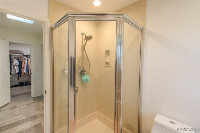 bathroom with a stall shower, toilet, and wood finished floors