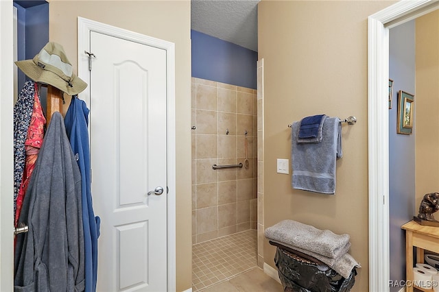 bathroom with tile patterned flooring, a textured ceiling, and tiled shower