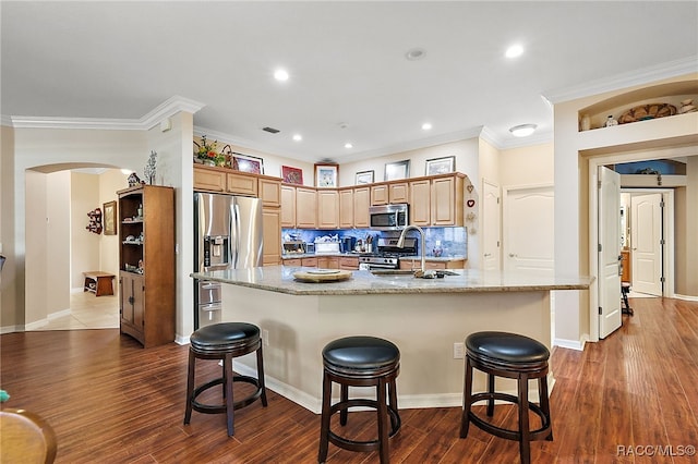 kitchen with dark hardwood / wood-style flooring, stainless steel appliances, a center island with sink, and a breakfast bar area