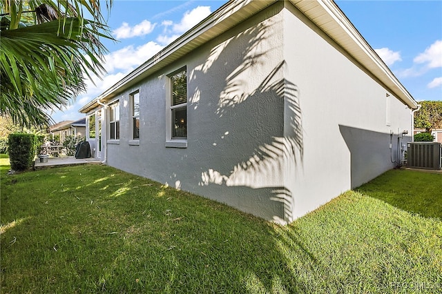 view of side of home with central AC unit and a lawn