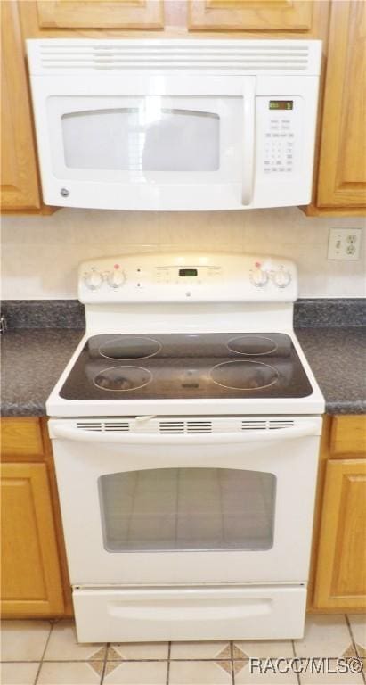 kitchen featuring light tile patterned flooring and white appliances