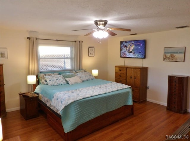 bedroom with ceiling fan, hardwood / wood-style floors, and a textured ceiling