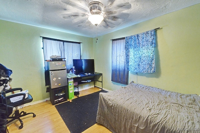 bedroom featuring ceiling fan, hardwood / wood-style floors, and a textured ceiling