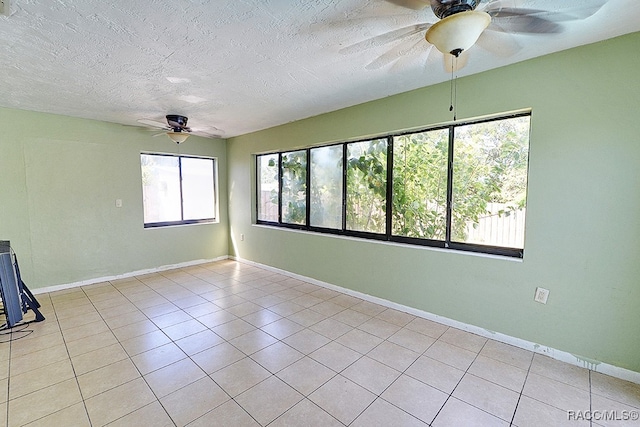 empty room with ceiling fan, light tile patterned floors, and a textured ceiling