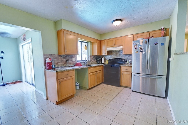 kitchen with backsplash, stainless steel refrigerator, light stone countertops, and black range with electric cooktop